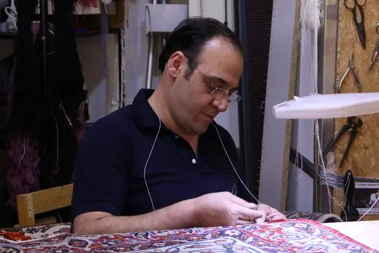 Parviz Moslemi arbeitet in der Werkstatt an einem Teppich